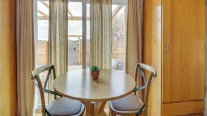 Un coin repas comprenant une table ronde, deux chaises, une plante en pot et un meuble en bois.