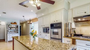 A kitchen with granite countertops, stainless steel appliances, and white cabinetry. - Pool, Hot Tub & Pool Table! Grand Home in Tomball (Tomball)
