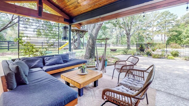 An outdoor patio with a wooden ceiling, a sofa, a coffee table, wicker chairs, and a hammock. - Pool, Hot Tub & Pool Table! Grand Home in Tomball (Tomball)