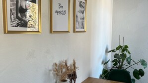 A dining area with a wooden table, two framed pictures on the wall, and a potted plant.