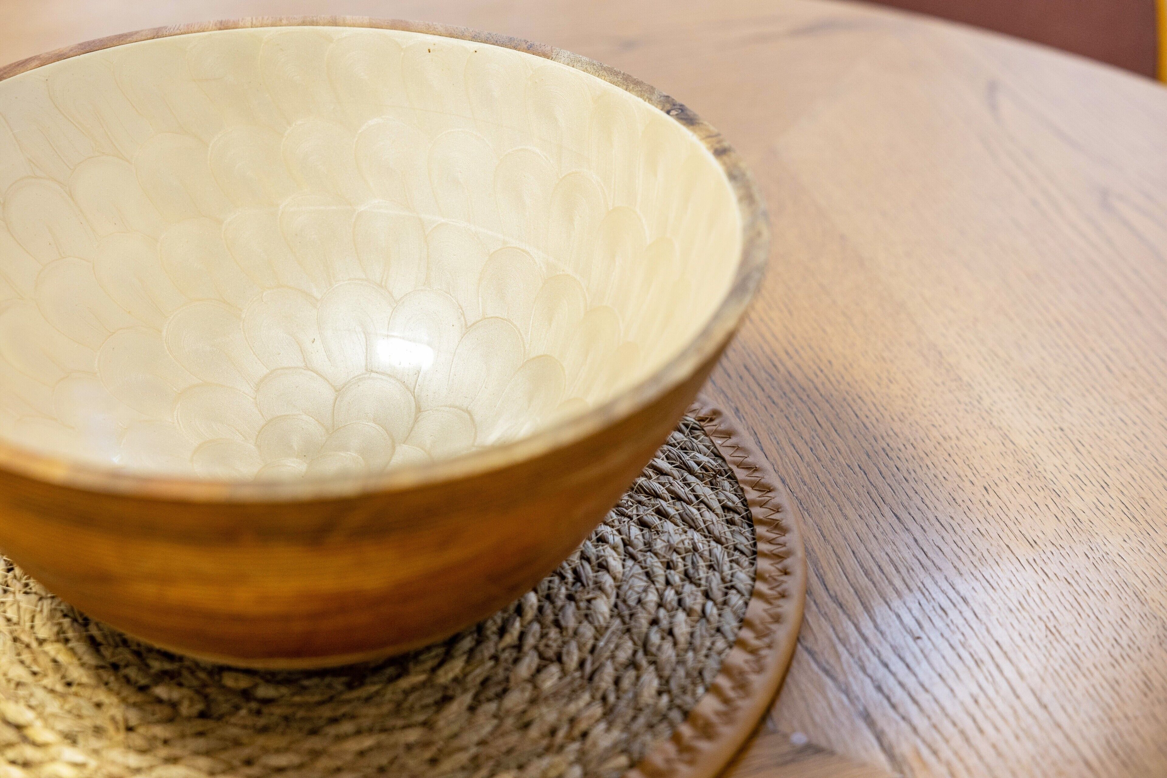 A wooden bowl on a woven placemat.