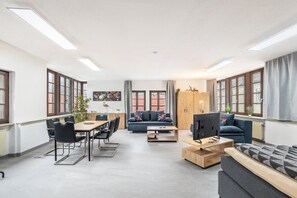 Ein modernes Wohnzimmer mit Sofa, Couchtisch, Fernseher und Essbereich.