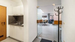 Una cocina moderna con armarios blancos, encimera gris y puerta de madera.