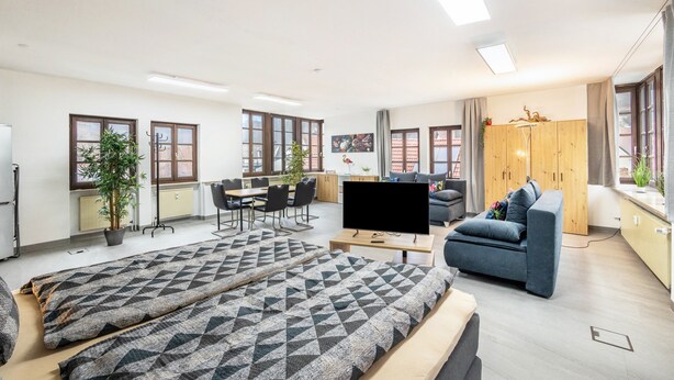 Una sala moderna con sofá, televisor y comedor.