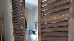 Una porta di legno con una decorazione in macramè e una scopa appoggiata al muro.