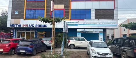 A building with multiple businesses including 'Aditya Inn A/C Rooms' and 'New Holland Agriculture'.