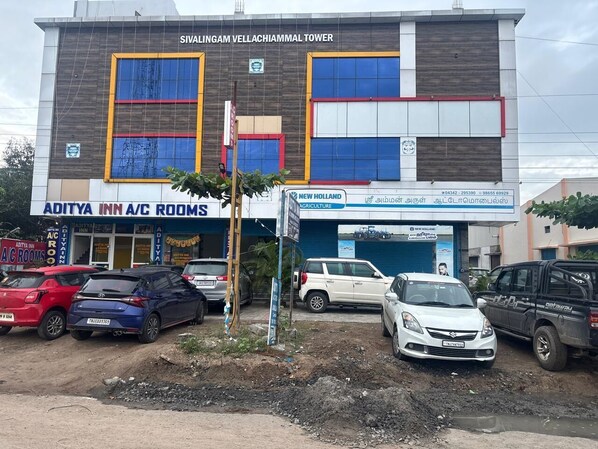 A building with multiple businesses including 'Aditya Inn A/C Rooms' and 'New Holland Agriculture'.