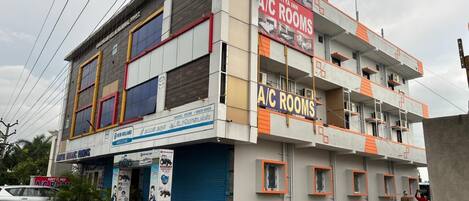 A multi-story building with signage for 'Aditya Inn' and 'A/C Rooms'.