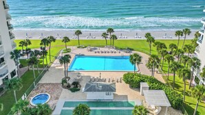 Un complexe hôtelier doté d’une piscine, d’un accès à la plage et de palmiers.