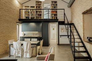 Ein kompakter Wohnraum mit Küche, Essbereich und einer Schlafempore mit Bücherregalen.