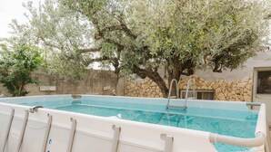 Une piscine extérieure avec un mur en pierre et un arbre en arrière-plan.