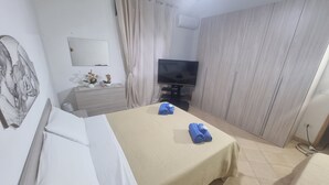 Une chambre d’hôtel avec un lit, une télévision, une commode et un rideau.