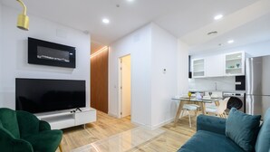 A modern living room with a flat-screen TV, green armchair, and blue sofa. - Spacious 2-bedroom flat in the centre of Madrid. (Madrid)