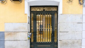 A black metal gate with the number 14 above it, set in a yellow and gray building facade. - Spacious 2-bedroom flat in the centre of Madrid. (Madrid)