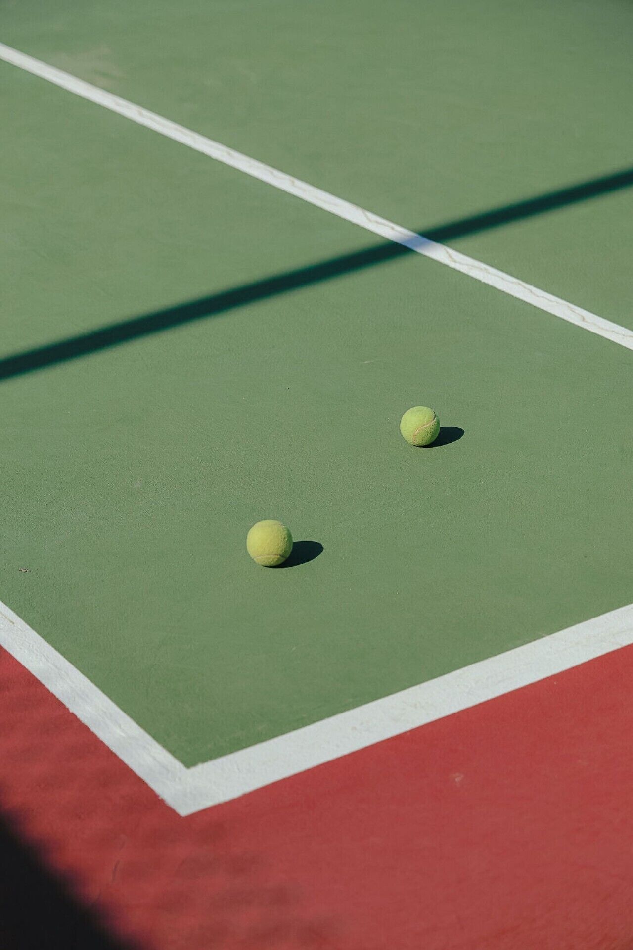 Un court de tennis avec deux balles de tennis et une ombre.