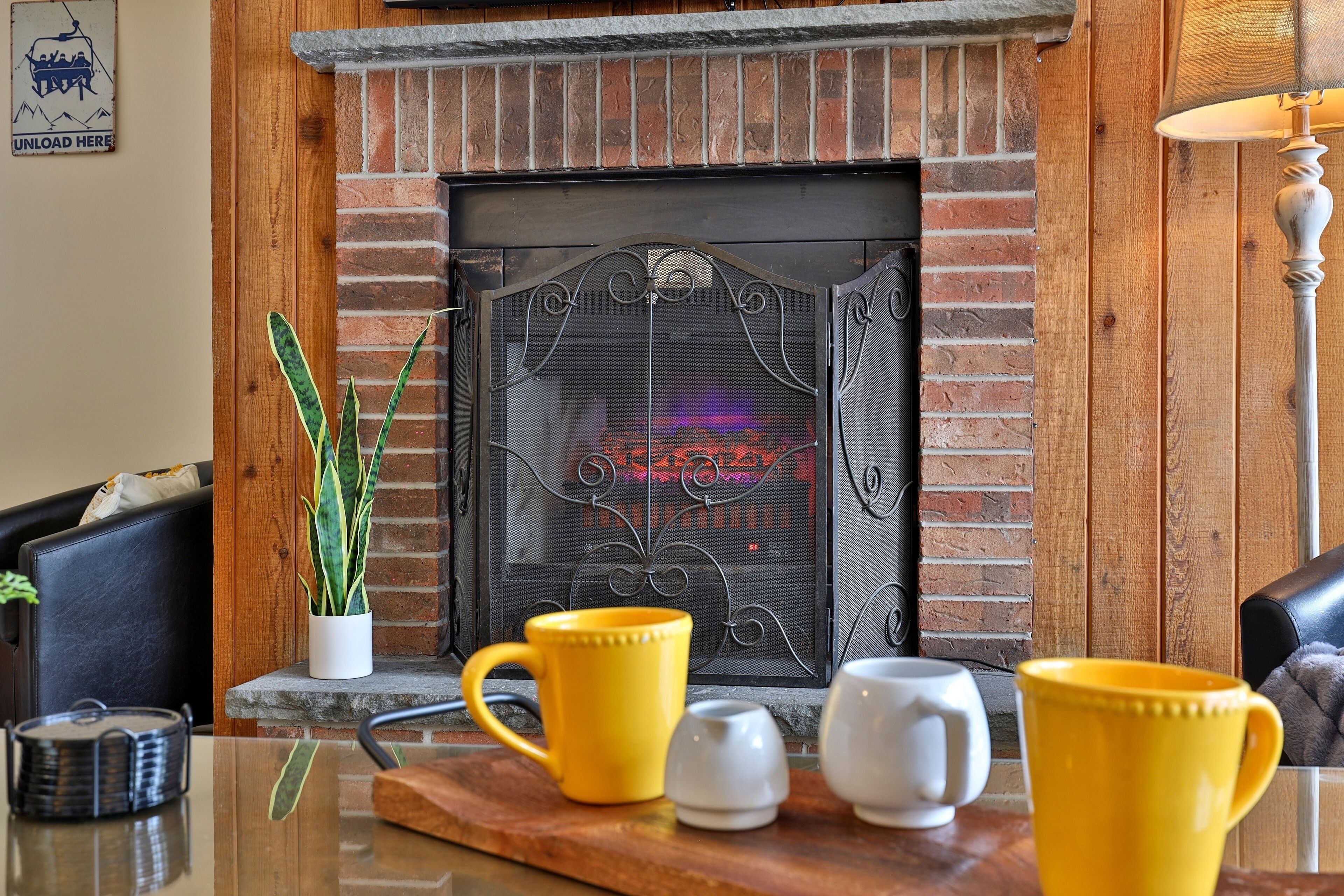 A fireplace with a metal screen, a wooden mantel, and a potted plant beside it.