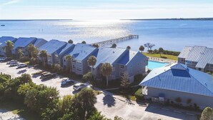 Een kusthotel met meerdere gebouwen met blauwe daken, een zwembad en een pier die het water in reikt.
