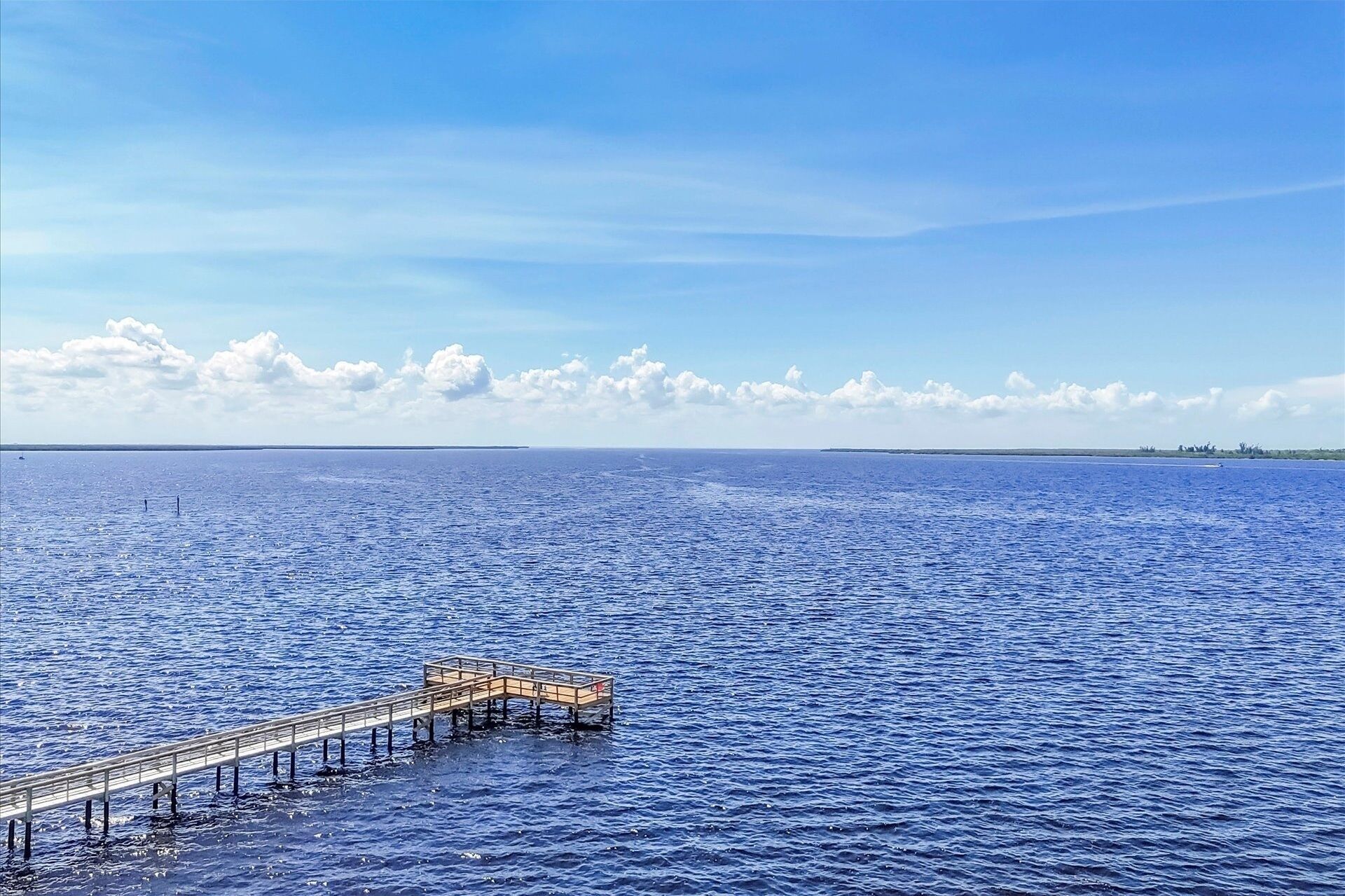 A pier extending into a calm sea under a clear sky.