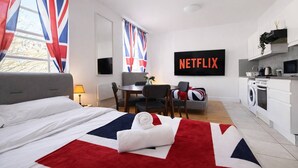 A hotel room with a bed, a dining area, a TV, and a kitchenette. - Central London (9) Apartment - Hyde Park (Greater London)