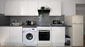 A modern kitchen with white cabinets, a washing machine, an oven, a microwave, and a refrigerator. - Central London (9) Apartment - Hyde Park (Greater London)