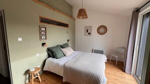 A bedroom with a bed, a stool, a chair, a wall-mounted shelf, and a window. - Apartment 'Les Iris - Cozy House', near Puy du Fou, Clisson and Nantes Vineyards (Montfaucon)