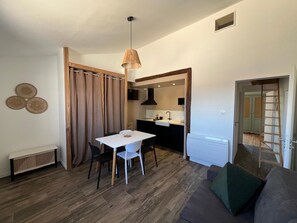Ett kompakt bostadsutrymme med en matplats, ett litet kök och en soffa.