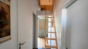 A narrow hallway with a wooden ladder leading to a lofted area, a door with a handle, and a poster on the wall. - Apartment 'Les Iris - Cozy House', near Puy du Fou, Clisson and Nantes Vineyards (Montfaucon)