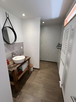 Une salle de bain moderne avec un meuble-lavabo en bois, un lavabo blanc et un grand miroir.