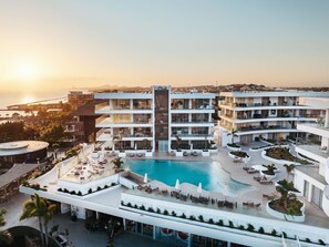 A resort with a central pool, multiple balconies, and a view of the sunset. - Penthouse • Oceanfront 2BR Luxury • ONE Mambo 36 (Willemstad)