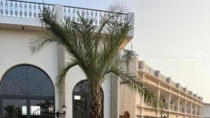 A building with a modern architectural style, featuring a large arched entrance and a palm tree in the foreground. - Narwar Lakefront Resort (Shivpuri)