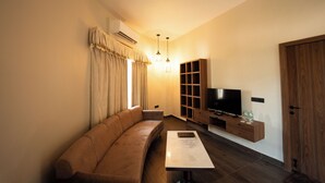 A modern living room with a brown sofa, a TV on a wooden stand, and a coffee table. - Narwar Lakefront Resort (Shivpuri)