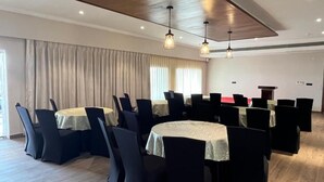 A conference room with round tables, black chairs, and a wooden ceiling. - Narwar Lakefront Resort (Shivpuri)