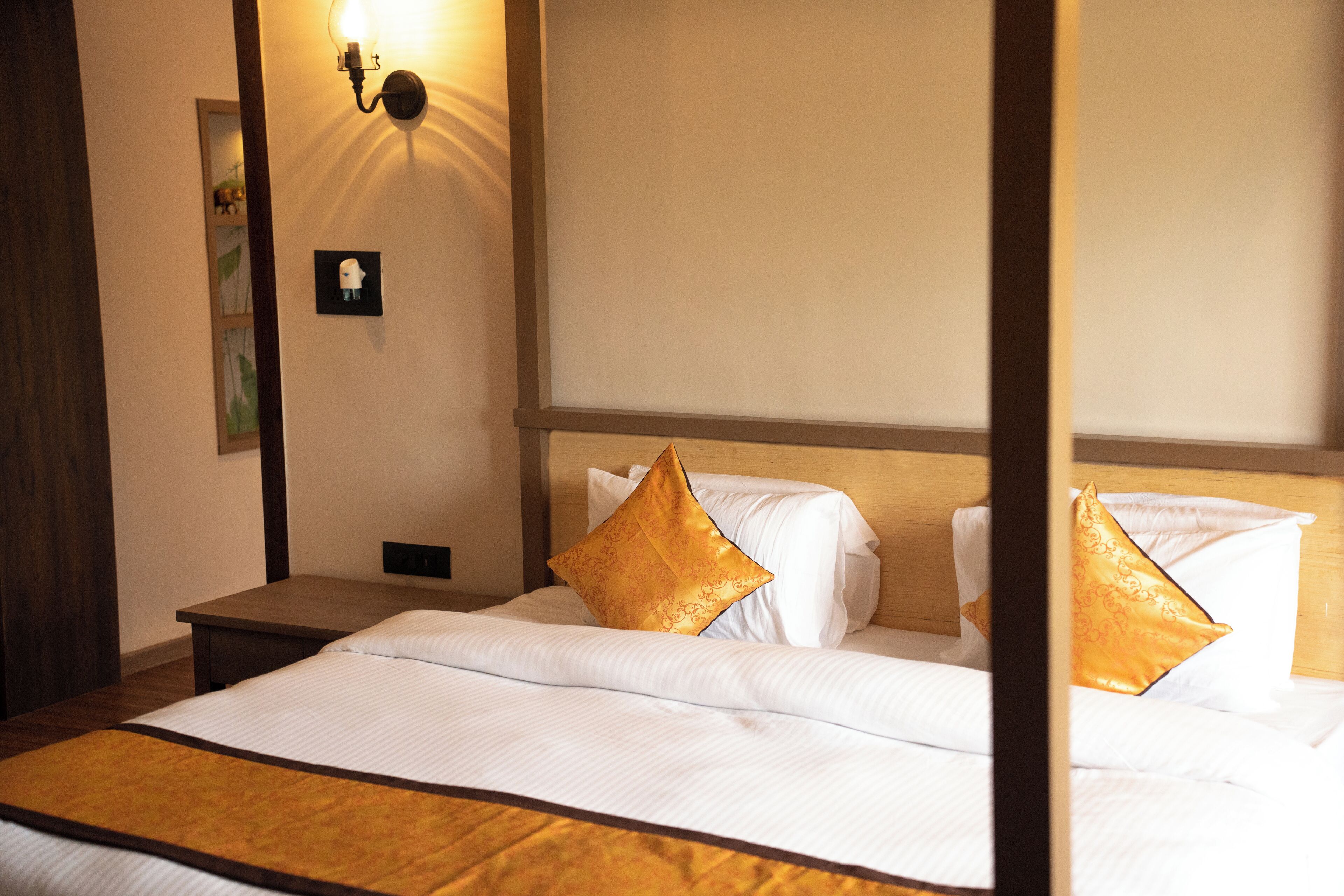 A hotel room with a bed, a nightstand, and a wall-mounted light fixture.