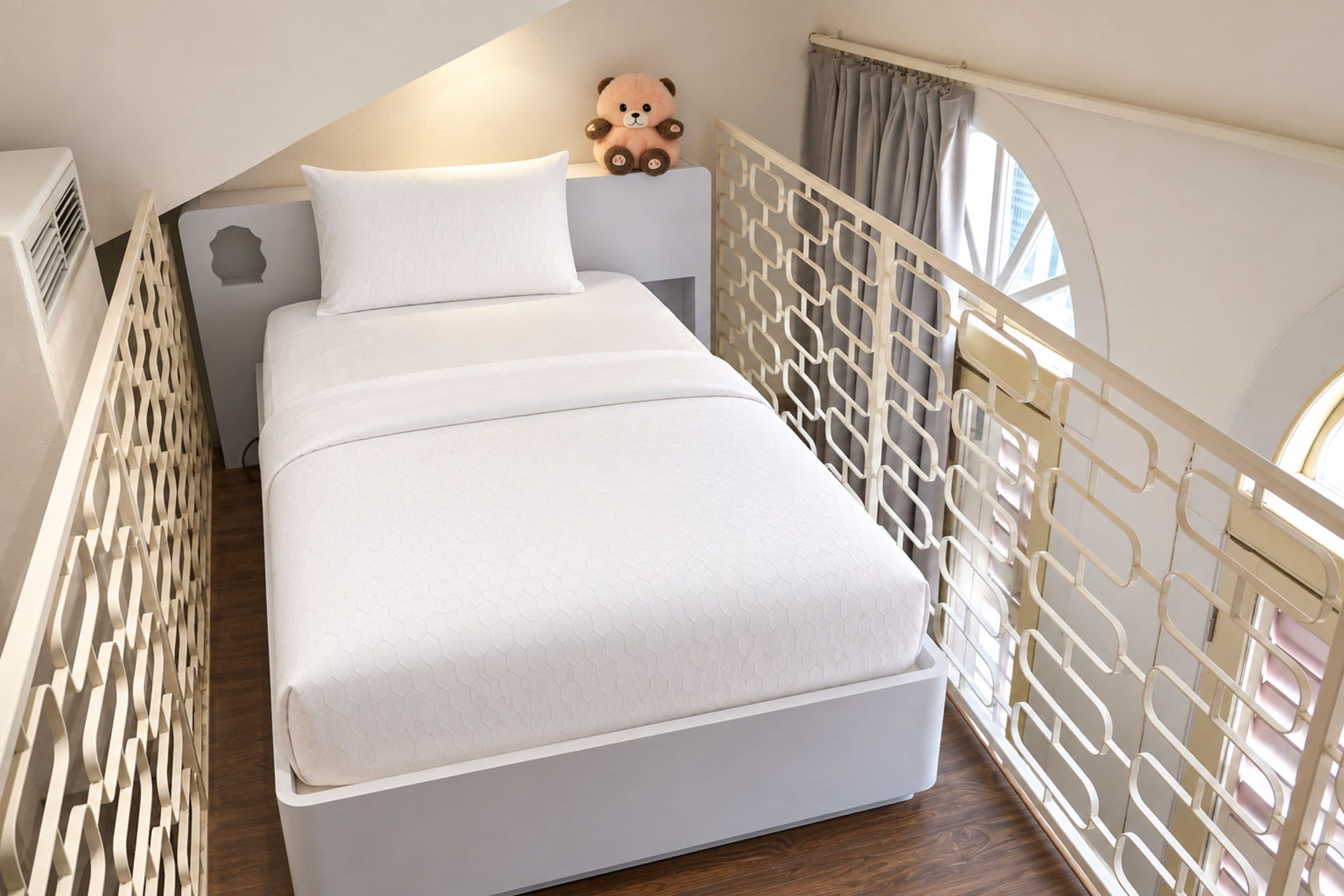 Un dormitorio con una cama, un oso de peluche y una ventana con cortinas.