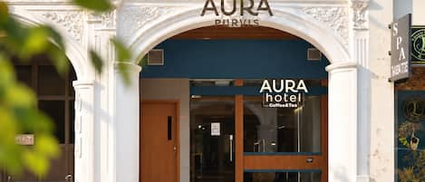 A hotel entrance with an ornate archway, a wooden door, and a glass facade.