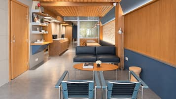 Un área de recepción moderna con un mostrador de madera, un sofá negro y dos sillas azules.