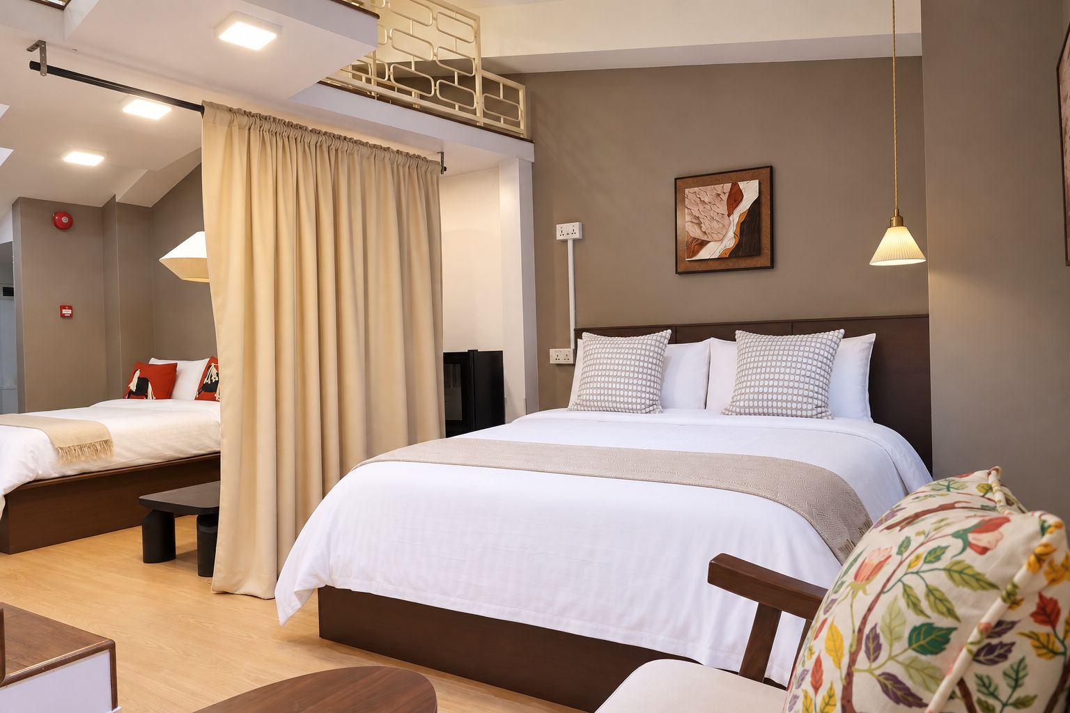 A hotel room with a large bed, a smaller bed, a desk, and a chair.