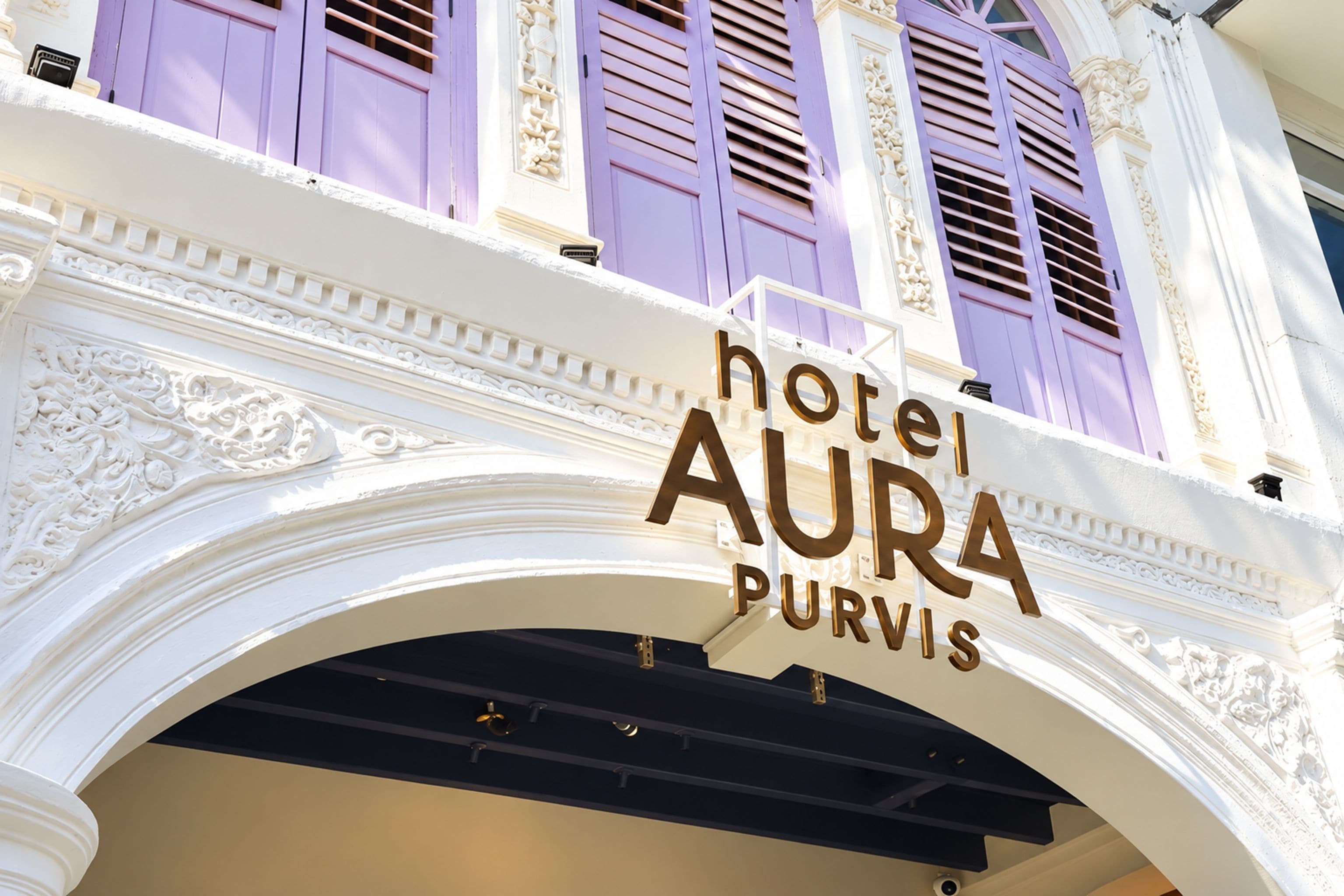 Letrero de hotel con el nombre 'hotel AURA PURVIS' en un estilo arquitectónico clásico con detalles ornamentales.