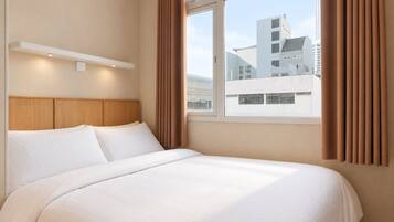 Une chambre d’hôtel avec un grand lit, une tête de lit en bois et une vue sur le paysage urbain par la fenêtre.