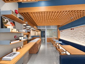 A modern interior with a long counter, seating area, and a patterned ceiling. - Aura Hotel Purvis (Singapore)