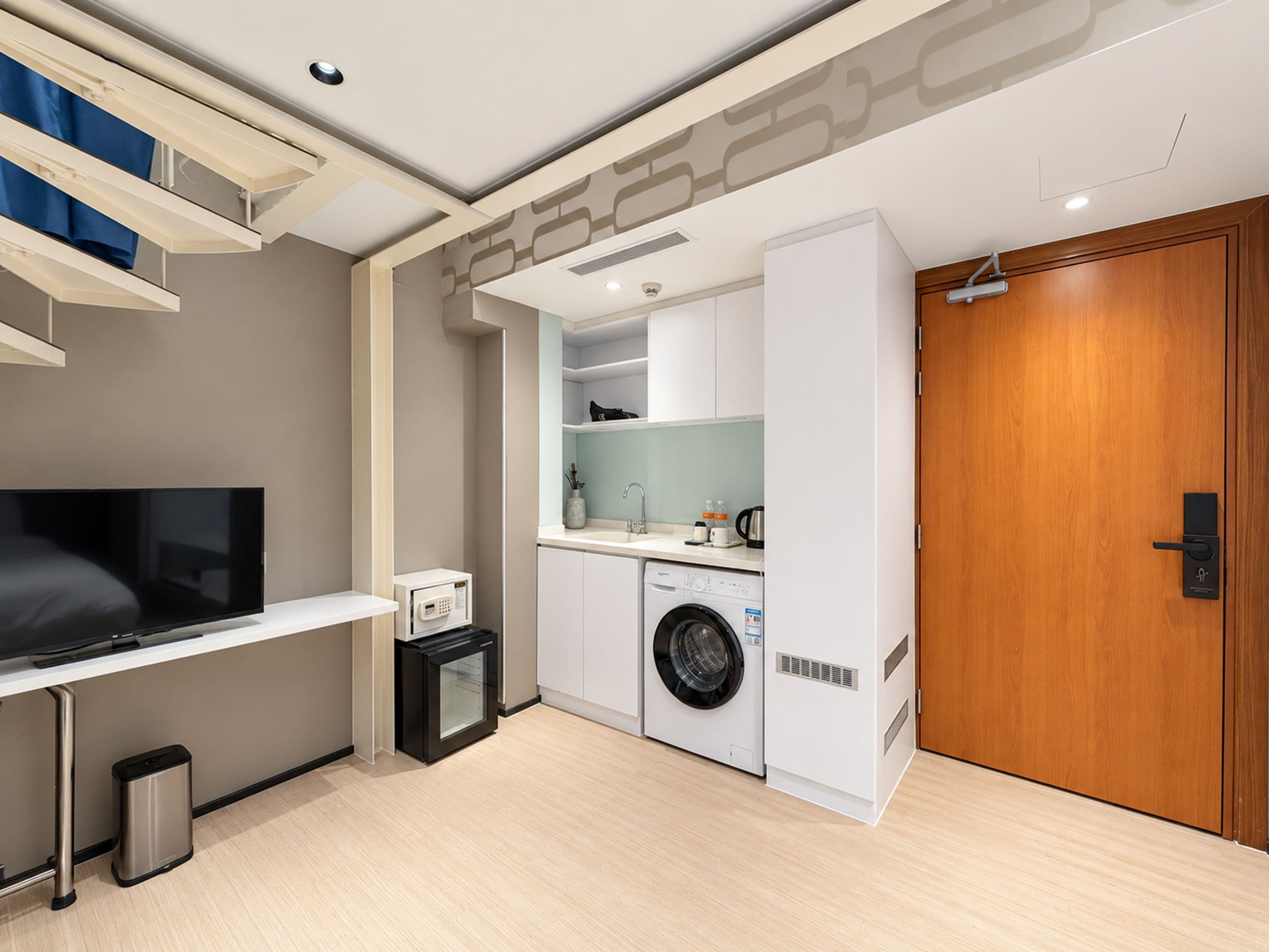Un espacio habitable funcional con televisor de pantalla plana, microondas, lavadora y puerta de madera.