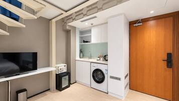Un espacio habitable funcional con televisor de pantalla plana, microondas, lavadora y puerta de madera.