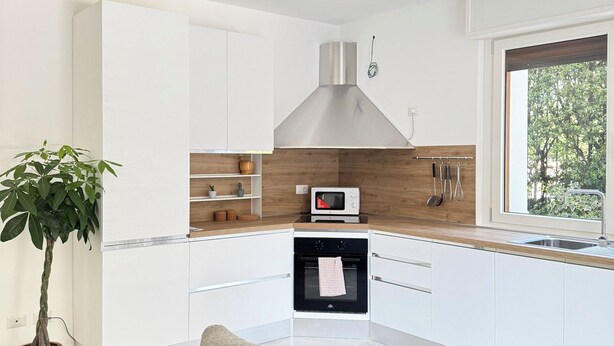A modern kitchen with white cabinets, a built-in oven, and a microwave. - Casa Mina (Opera)