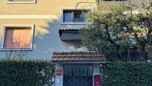 A multi-story building with a gated entrance, a small balcony with plants, and a clear blue sky. - Casa Mina (Opera)