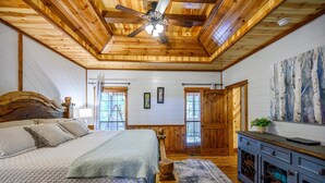 A bedroom with a wooden ceiling, a bed with a wooden headboard, a nightstand, a dresser, and a painting on the wall. - Treetop Hideaway, Shuffleboard, Hot Tub, Bunks, Games! Free Firewood (Broken Bow)