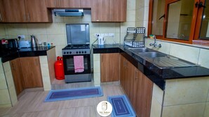 Une cuisine avec des meubles de rangement en bois, une cuisinière à gaz, un évier et une fenêtre avec des cadres en bois.