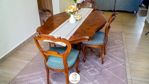 Un coin repas avec une table en bois, quatre chaises et un vase rempli de fleurs.
