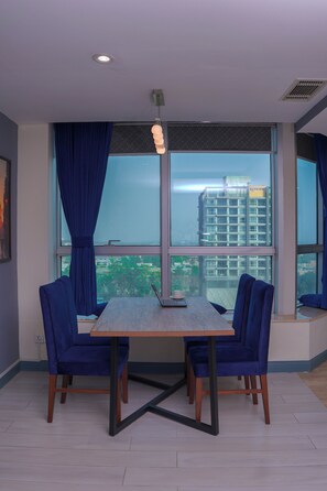 Ein modernes Zimmer mit großem Fenster, Tisch mit Stühlen und Blick auf eine Stadtansicht.