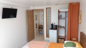 Une chambre avec un lit, une télévision, une armoire et un coin cuisine.