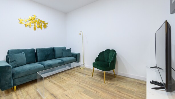 A modern living room with a teal sofa, a green armchair, and a clear glass coffee table. - M Scsd14 Amplio Piso Exterior de 2 Dormitorios e (Madrid)